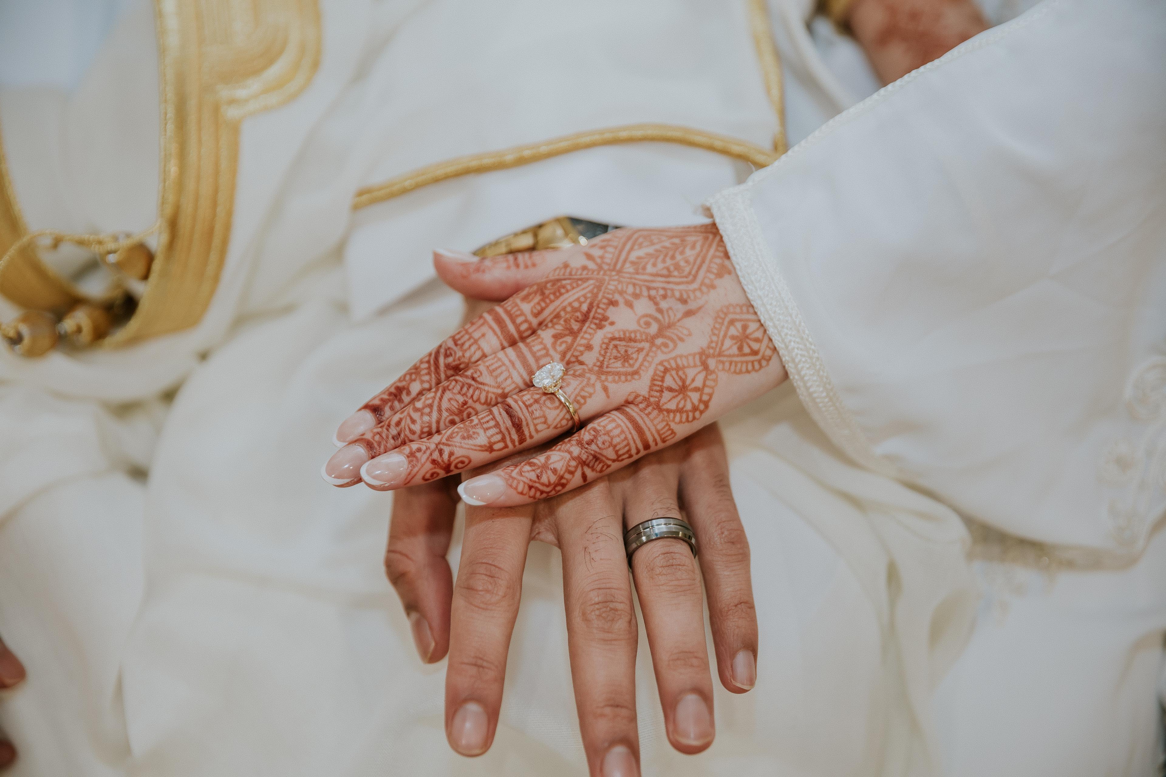 Couple holding hands during wedding ceremony — bride's ring visible