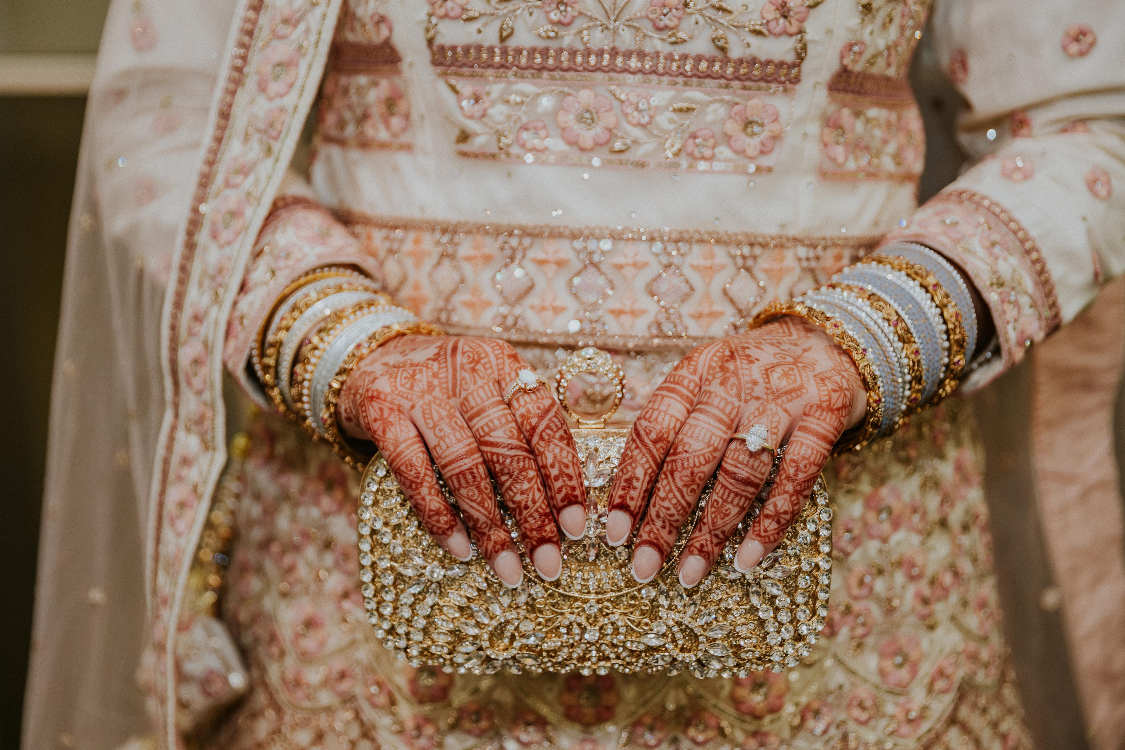 South Asian bride holding custom rings alongside a clutch
